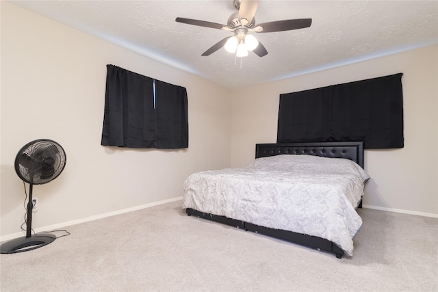 carpeted bedroom featuring ceiling fan and a textured ceiling