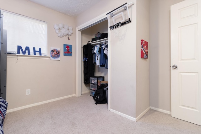 bedroom with a textured ceiling, light carpet, and a closet