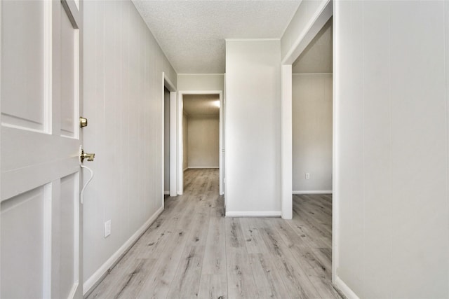 hall with light hardwood / wood-style flooring and a textured ceiling