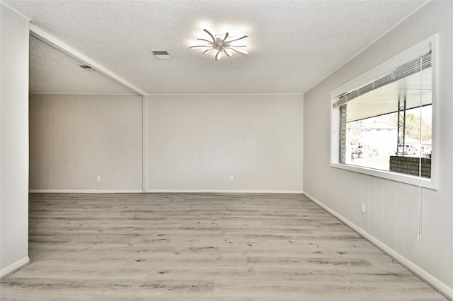 empty room featuring a textured ceiling and light wood-type flooring