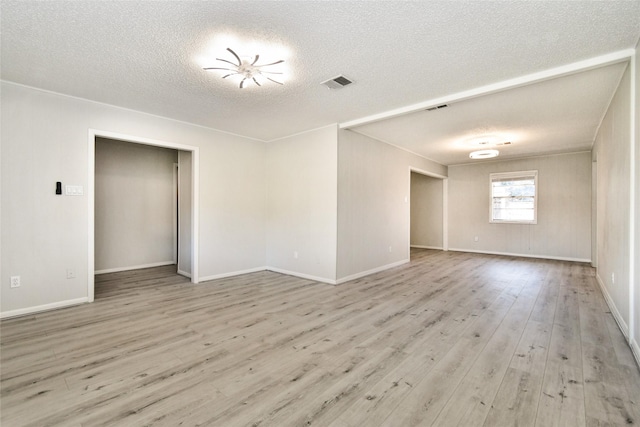 spare room with a textured ceiling and light wood-type flooring