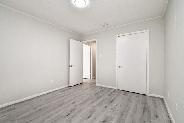 unfurnished bedroom featuring a textured ceiling, light hardwood / wood-style floors, and a closet