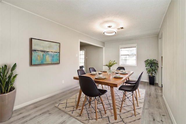 dining space featuring light hardwood / wood-style flooring and a textured ceiling