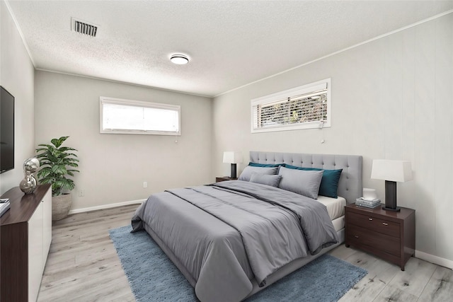 bedroom featuring light hardwood / wood-style floors and a textured ceiling