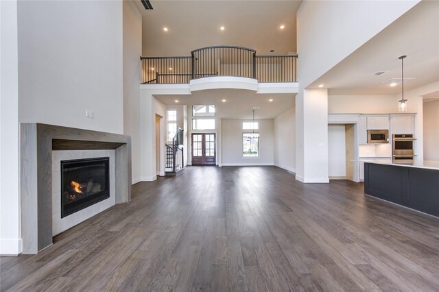 unfurnished living room with a towering ceiling, dark wood-type flooring, and a tiled fireplace