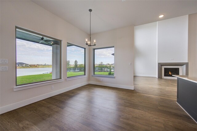 unfurnished dining area featuring a water view, dark wood-type flooring, and an inviting chandelier