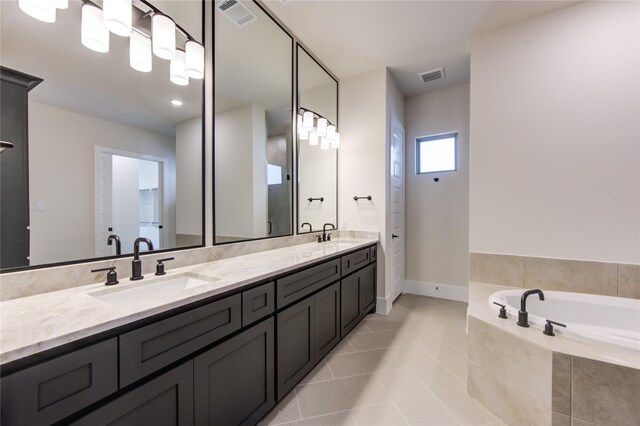 bathroom with tile patterned flooring, vanity, and tiled bath