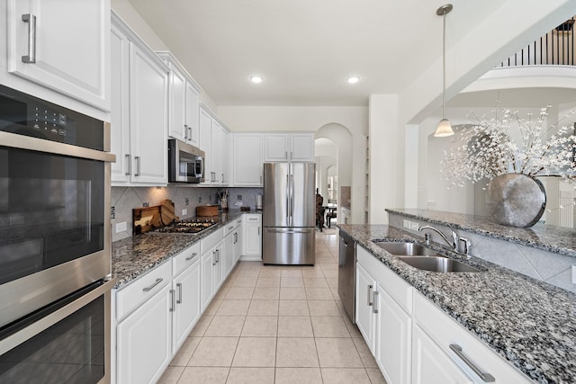 kitchen featuring hanging light fixtures, sink, appliances with stainless steel finishes, tasteful backsplash, and white cabinetry