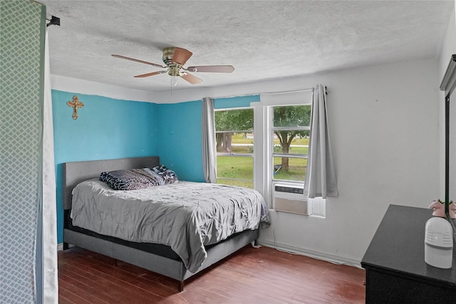 bedroom with ceiling fan, cooling unit, wood-type flooring, and a textured ceiling