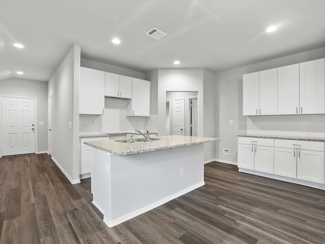 kitchen featuring white cabinets, a center island with sink, light stone countertops, and sink