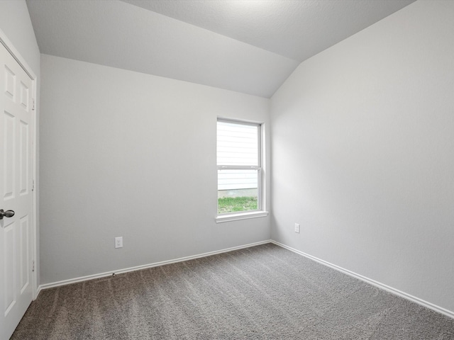 empty room with dark carpet, lofted ceiling, and a textured ceiling