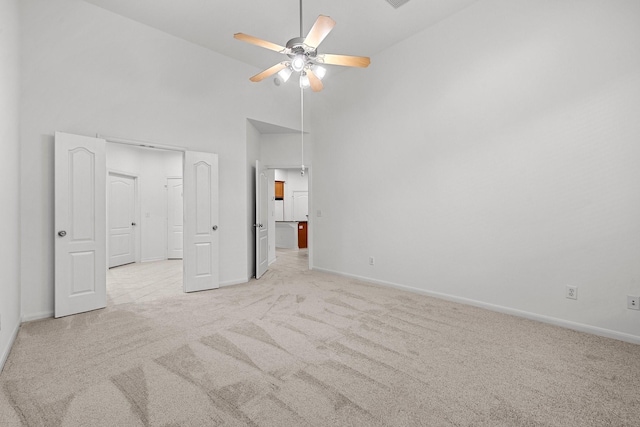 unfurnished bedroom featuring light colored carpet, high vaulted ceiling, and ceiling fan