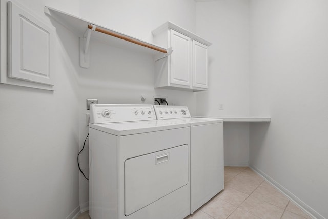 laundry room with cabinets, light tile patterned floors, and washing machine and dryer