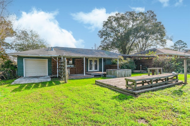 rear view of property featuring a yard, french doors, and a garage