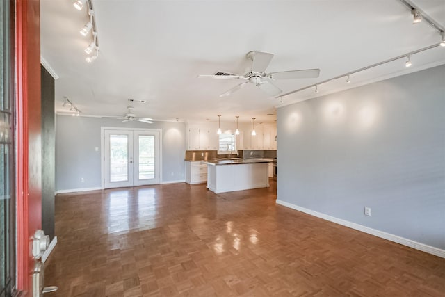 unfurnished living room with ceiling fan, french doors, and dark parquet floors