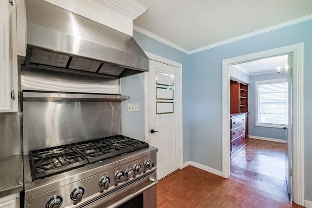 kitchen with parquet floors, white cabinets, high end stainless steel range, wall chimney exhaust hood, and ornamental molding