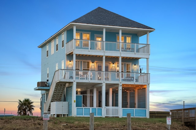 back house at dusk featuring a balcony and central AC unit