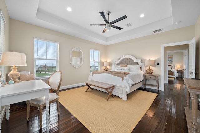 bedroom with ceiling fan, dark hardwood / wood-style flooring, and a raised ceiling