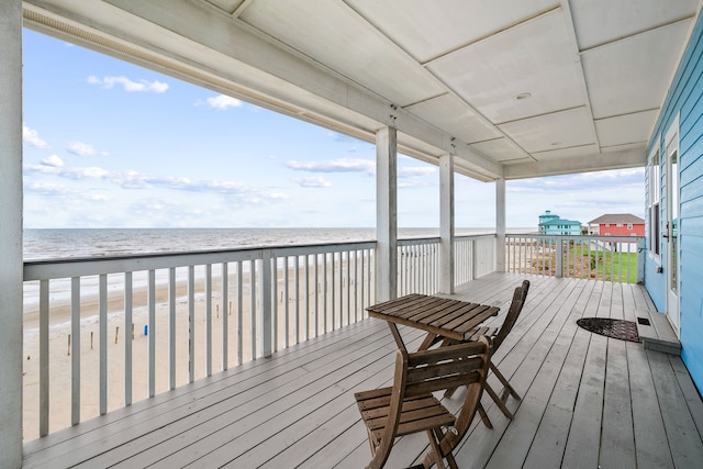 wooden deck featuring a water view and a beach view