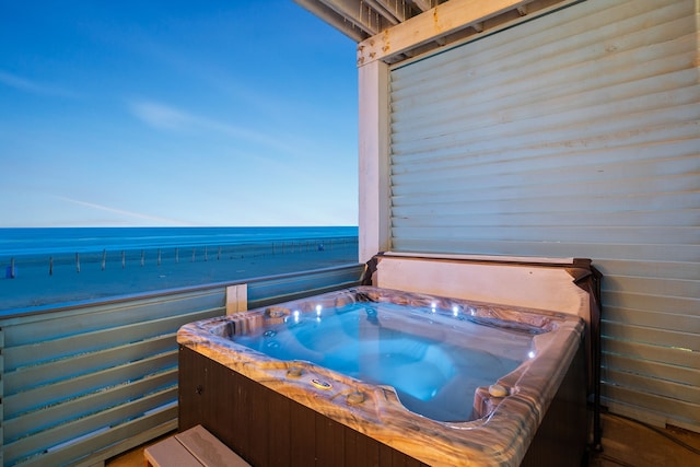 misc room with a jacuzzi, a water view, and a view of the beach