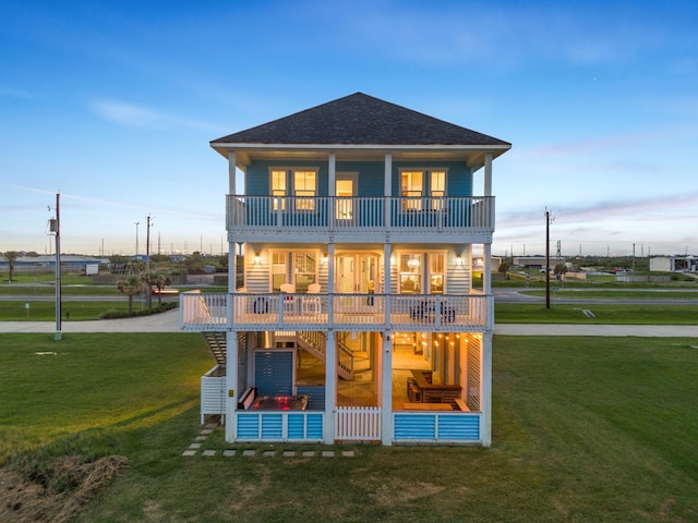 rear view of house featuring a balcony and a lawn