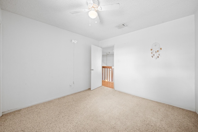 carpeted spare room featuring ceiling fan and a textured ceiling