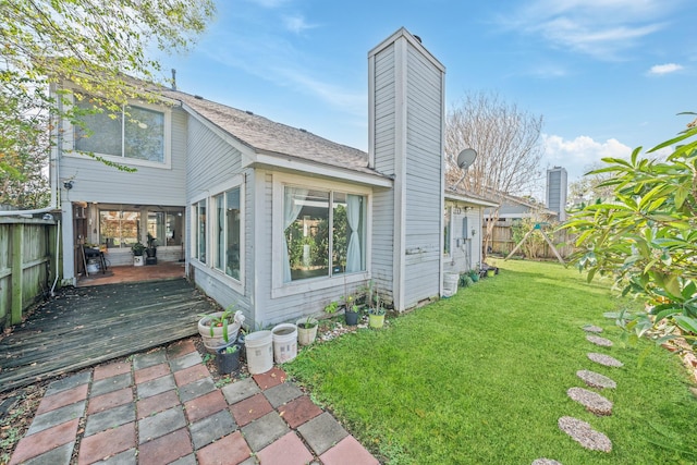 rear view of house featuring a wooden deck and a lawn