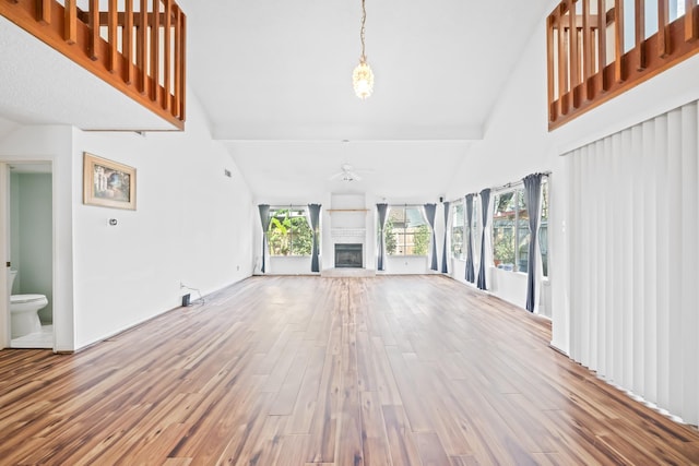 unfurnished living room with ceiling fan, hardwood / wood-style floors, and high vaulted ceiling