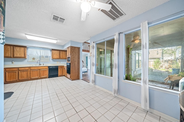 kitchen with a textured ceiling, sink, a healthy amount of sunlight, and black appliances