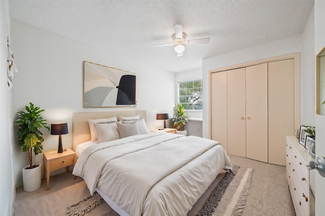 bedroom with ceiling fan, light colored carpet, and a closet