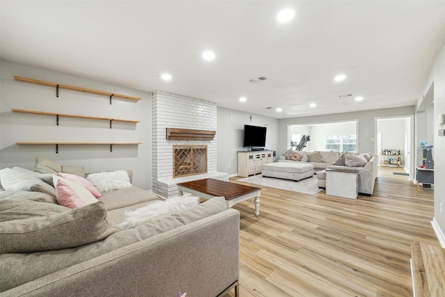 living room with light hardwood / wood-style floors and a brick fireplace