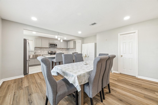 dining space with sink and light wood-type flooring