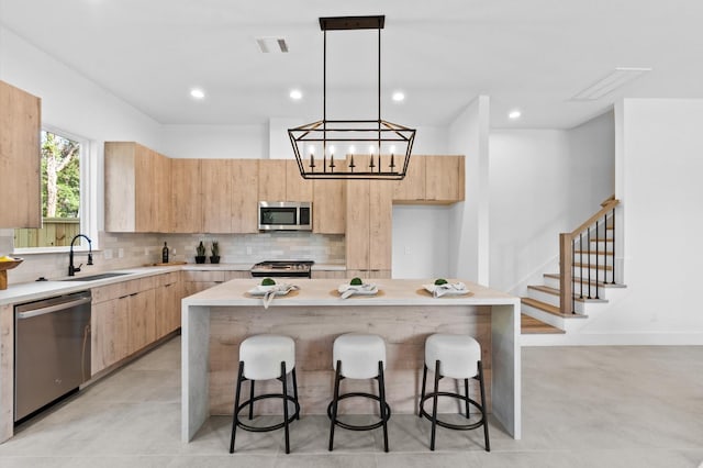 kitchen featuring decorative light fixtures, a center island, stainless steel appliances, and sink