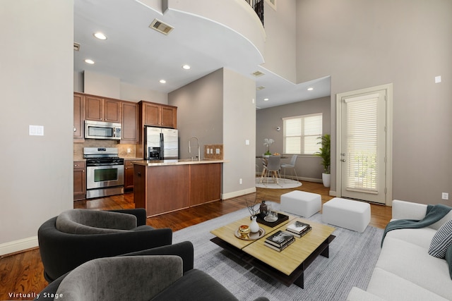 living room featuring sink, a high ceiling, and hardwood / wood-style flooring