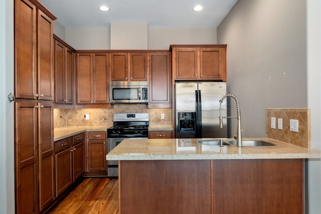 kitchen featuring kitchen peninsula, light stone countertops, tasteful backsplash, stainless steel appliances, and sink