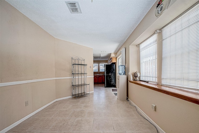 hallway with light tile patterned floors and a textured ceiling