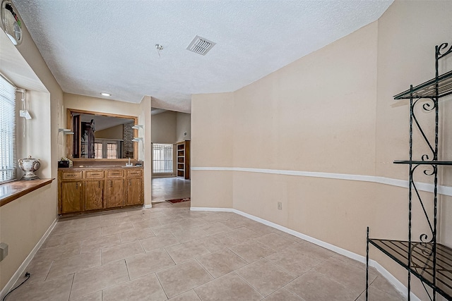 tiled spare room with a textured ceiling, plenty of natural light, and sink