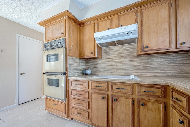 kitchen with backsplash, a textured ceiling, double oven, electric cooktop, and light tile patterned flooring