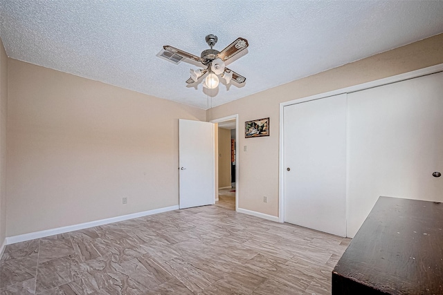 unfurnished bedroom with ceiling fan, a textured ceiling, and a closet