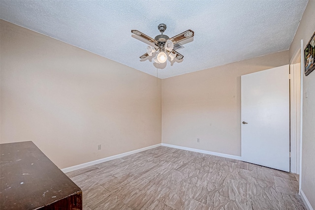 empty room with ceiling fan and a textured ceiling