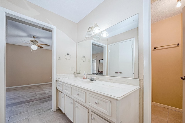 bathroom with tile patterned flooring, vanity, ceiling fan, and a textured ceiling