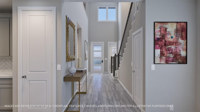 hall with light hardwood / wood-style floors and a towering ceiling