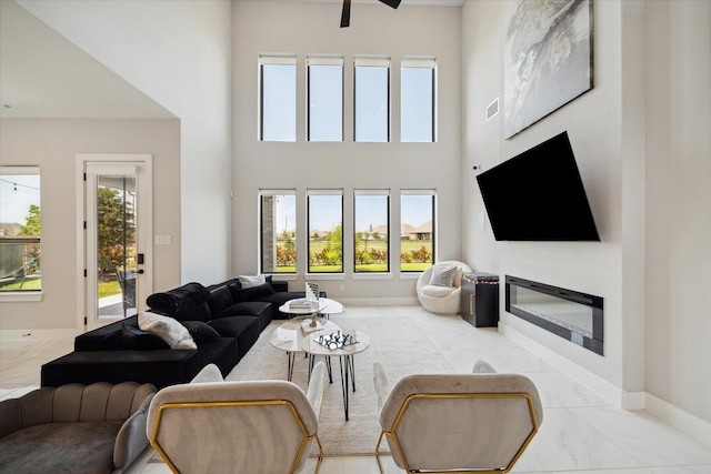 living room featuring baseboards, plenty of natural light, marble finish floor, and a glass covered fireplace