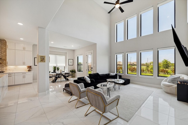 living room featuring recessed lighting, baseboards, plenty of natural light, and a high ceiling