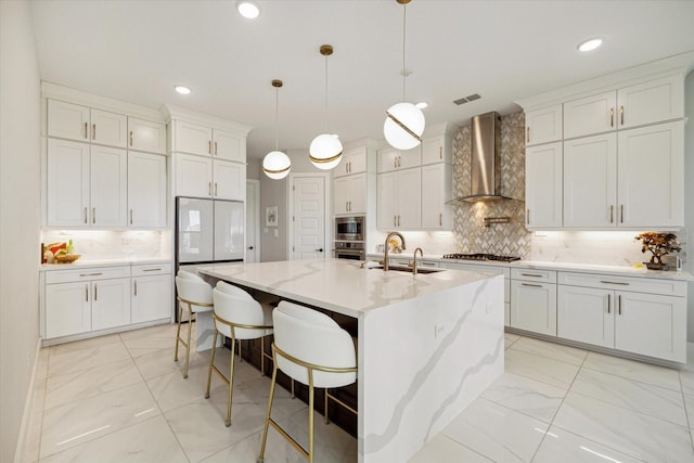 kitchen featuring white cabinets, stainless steel appliances, wall chimney exhaust hood, and a sink