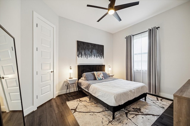 bedroom with dark wood-style floors, a ceiling fan, and baseboards