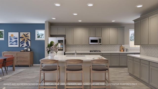 kitchen with a center island with sink, fridge, and gray cabinets