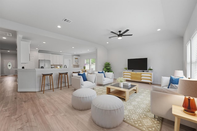 living room featuring ceiling fan, vaulted ceiling, and light hardwood / wood-style flooring