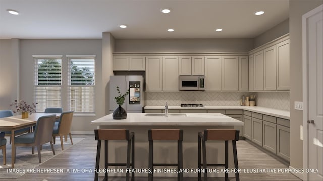 kitchen featuring sink, a kitchen breakfast bar, refrigerator, and a kitchen island with sink