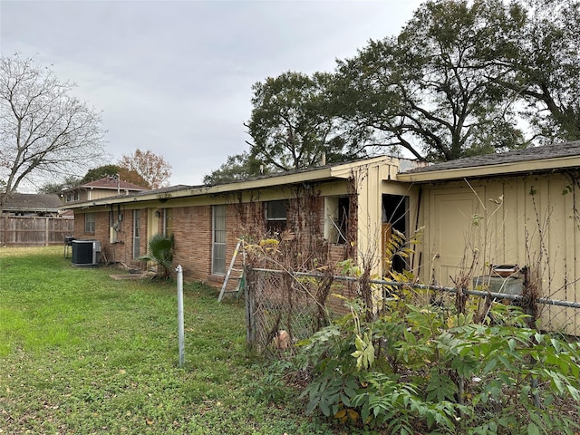 rear view of property with a lawn and cooling unit